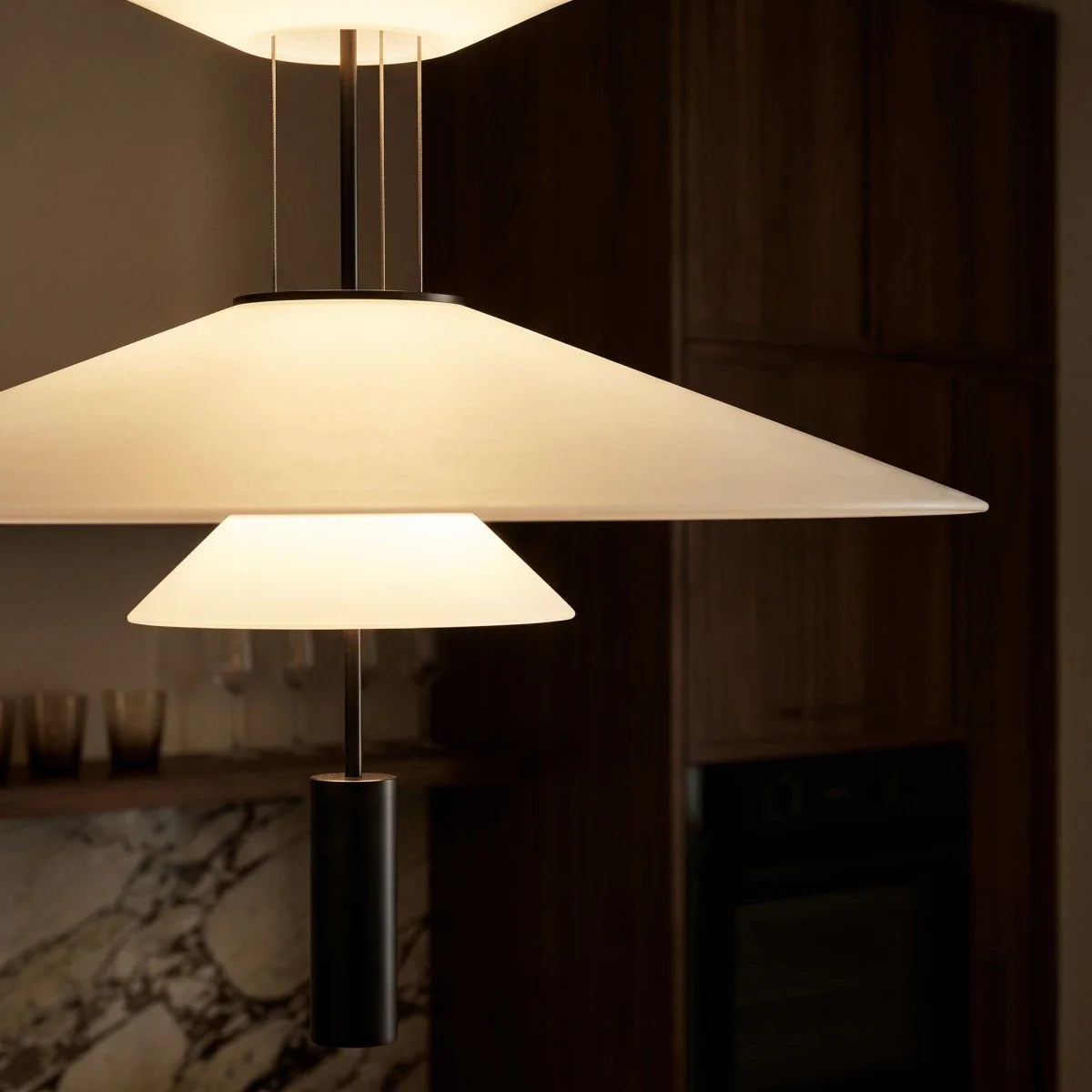Close view of a Clérachic pendant with a wide white frosted shade, a small cone and a black cylinder weight.