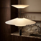 Clérachic tiered pendant with frosted white discs and a black cylinder, lit beside walnut cabinets and a marble splashback.