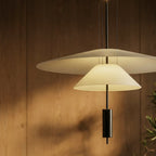 Clérachic pendant with a wide white shade over a small glowing cone, on a black rod against warm wood panelling.