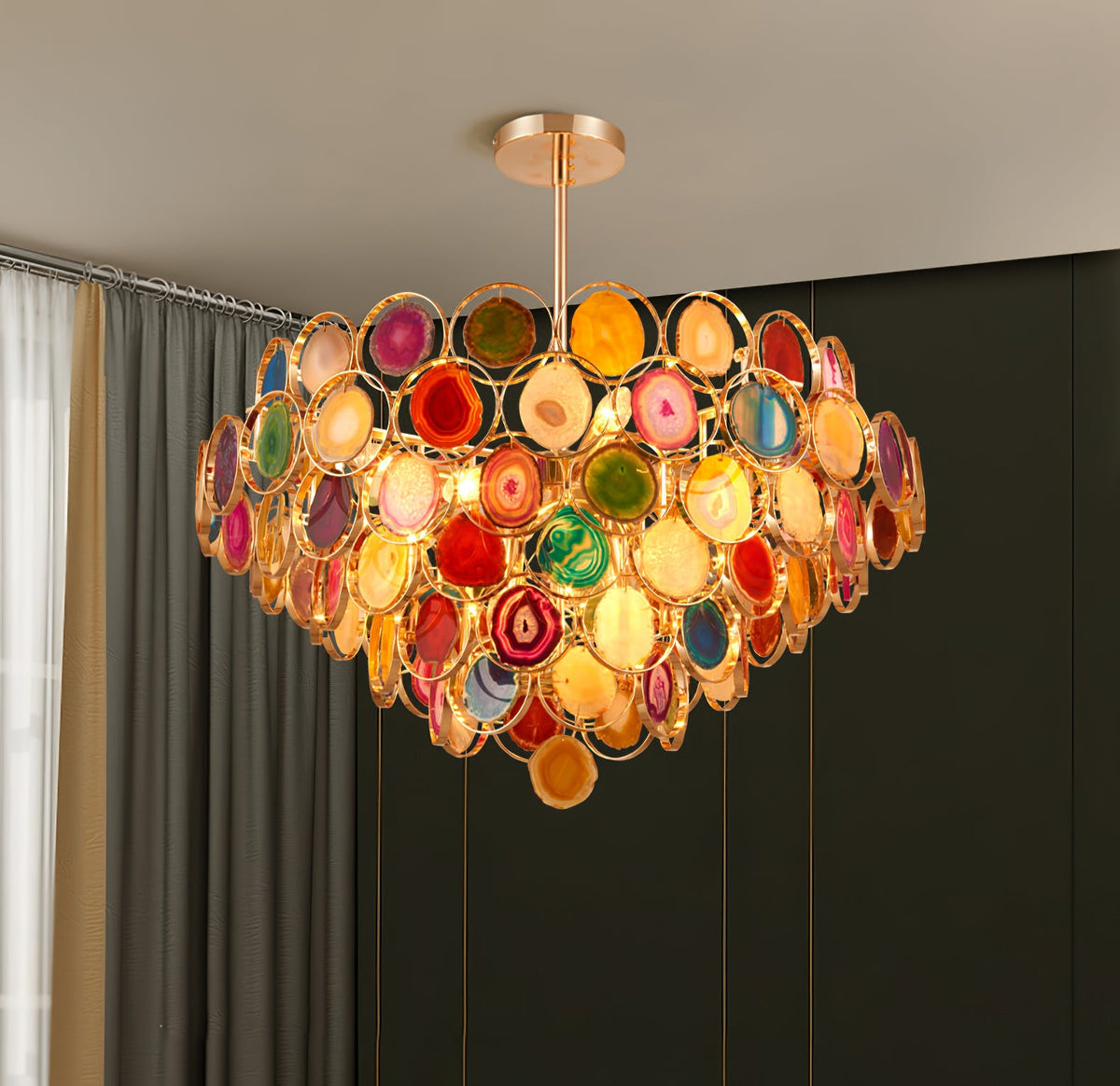 Clérachic agate chandelier lit against a dark wall and grey curtain, its stone slices glowing red, green and amber.