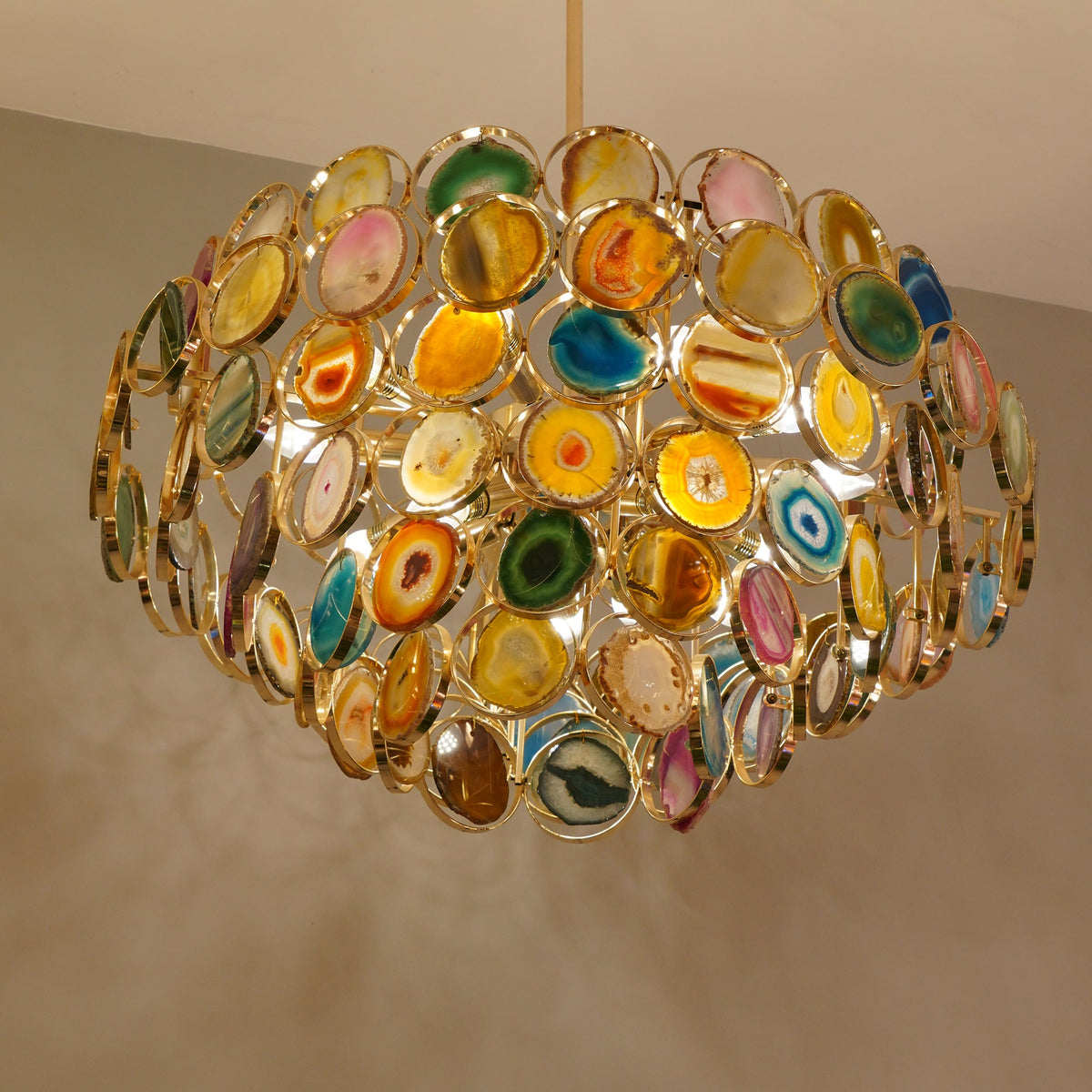 Close view of the stone slices and gold rings on this Clérachic agate chandelier, lit from within.