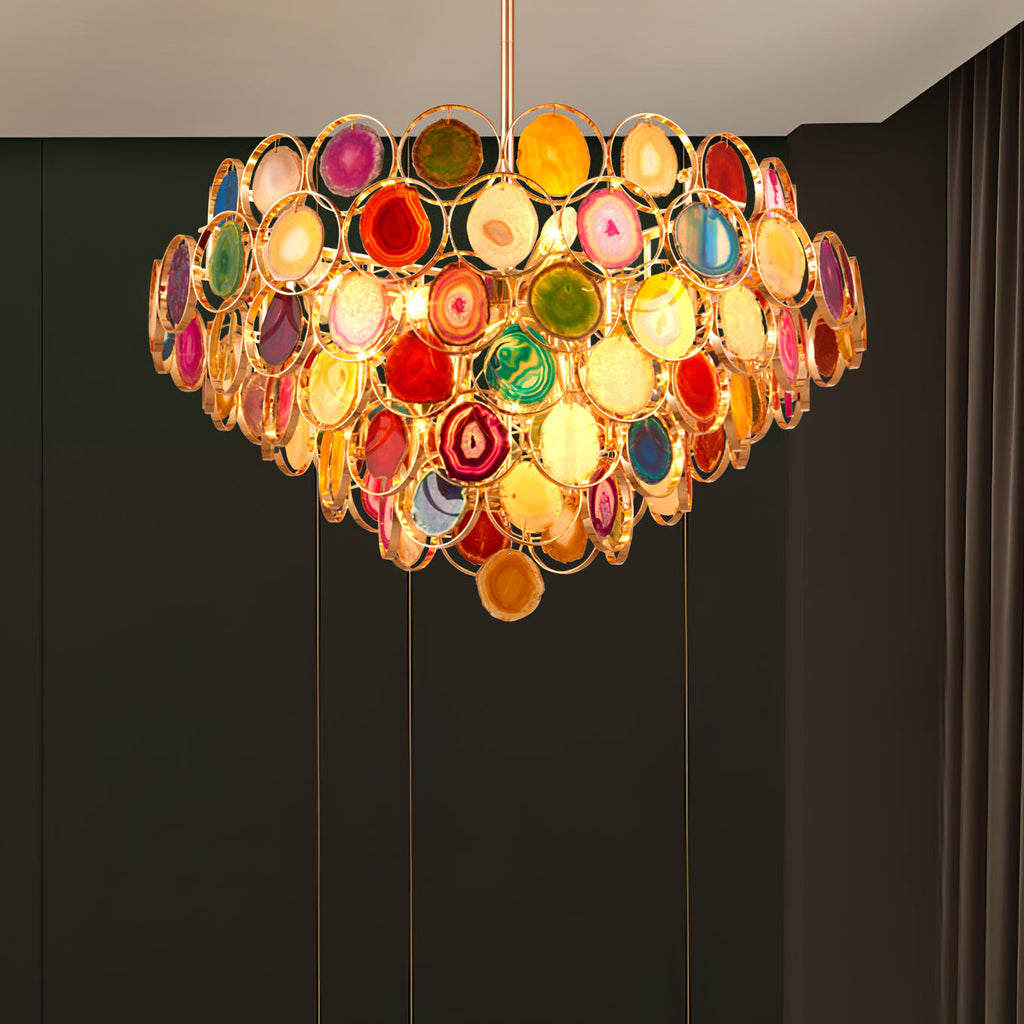 A Clérachic agate chandelier glowing against dark panelling, its stone slices in red, gold and green.