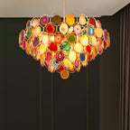 A Clérachic agate chandelier glowing against dark panelling, its stone slices in red, gold and green.