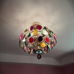 Looking up at a Clérachic agate chandelier on a grey ceiling, its stone slices in pink, teal and gold catching the light.