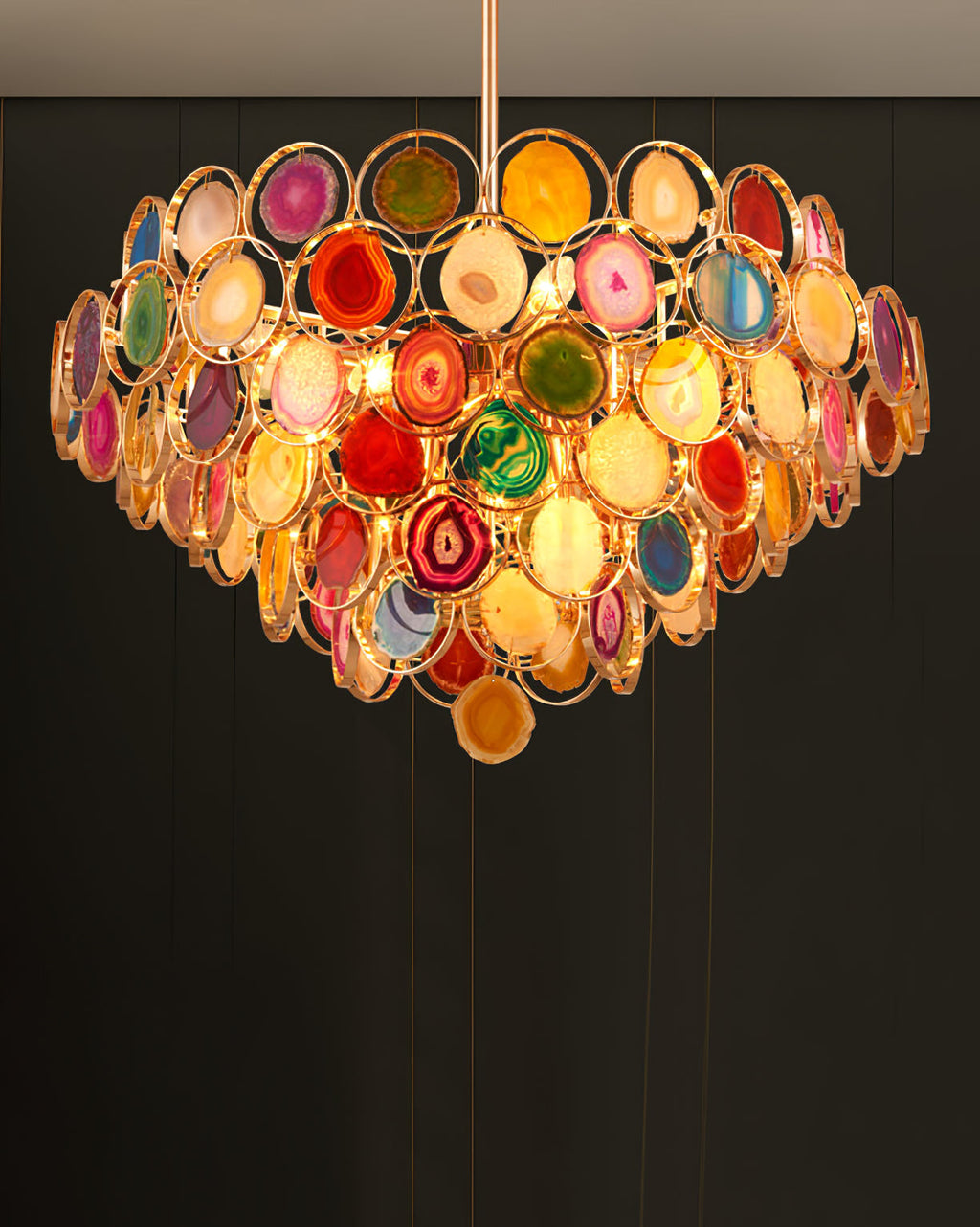 A Clérachic agate chandelier glowing in a dark room, with fine wires and a warm light below the lower tier.