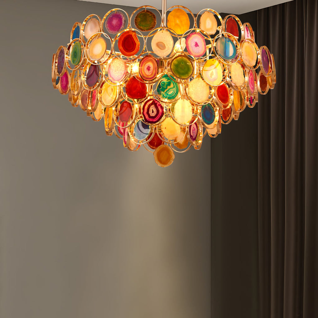 Clérachic agate chandelier lit against a dark grey wall with a pale pool of light on the wall behind.