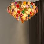 Clérachic agate chandelier lit against a dark grey wall with a pale pool of light on the wall behind.