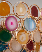 Close detail of agate slices in pink, blue, green and amber, each held in a thin gold ring on this Clérachic chandelier.