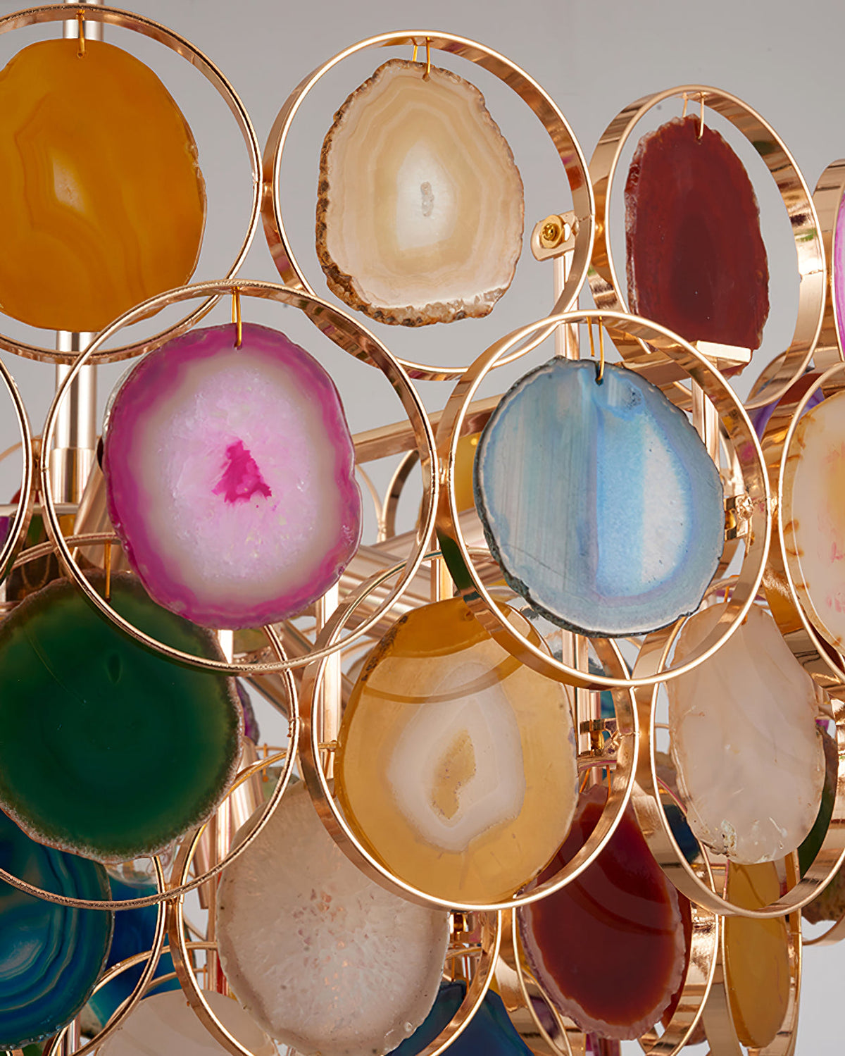 Close detail of agate slices in pink, blue, green and amber, each held in a thin gold ring on this Clérachic chandelier.
