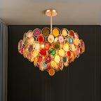 Clérachic agate chandelier lit on a dark green wall, its tiers of stone slices glowing warm at the centre.