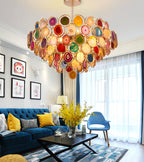 A Clérachic agate chandelier above a blue velvet sofa and coffee table, in a room with framed prints and white curtains.