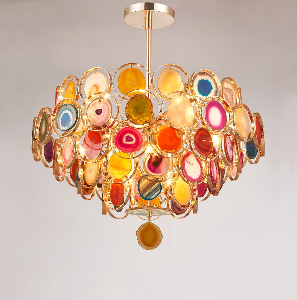 Clérachic agate chandelier on a soft grey wall, with its rod and canopy above tiers of lit stone slices.