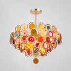 Multicolour Clérachic agate chandelier on a pale grey backdrop, showing red, amber, blue and pink slices lit from inside.