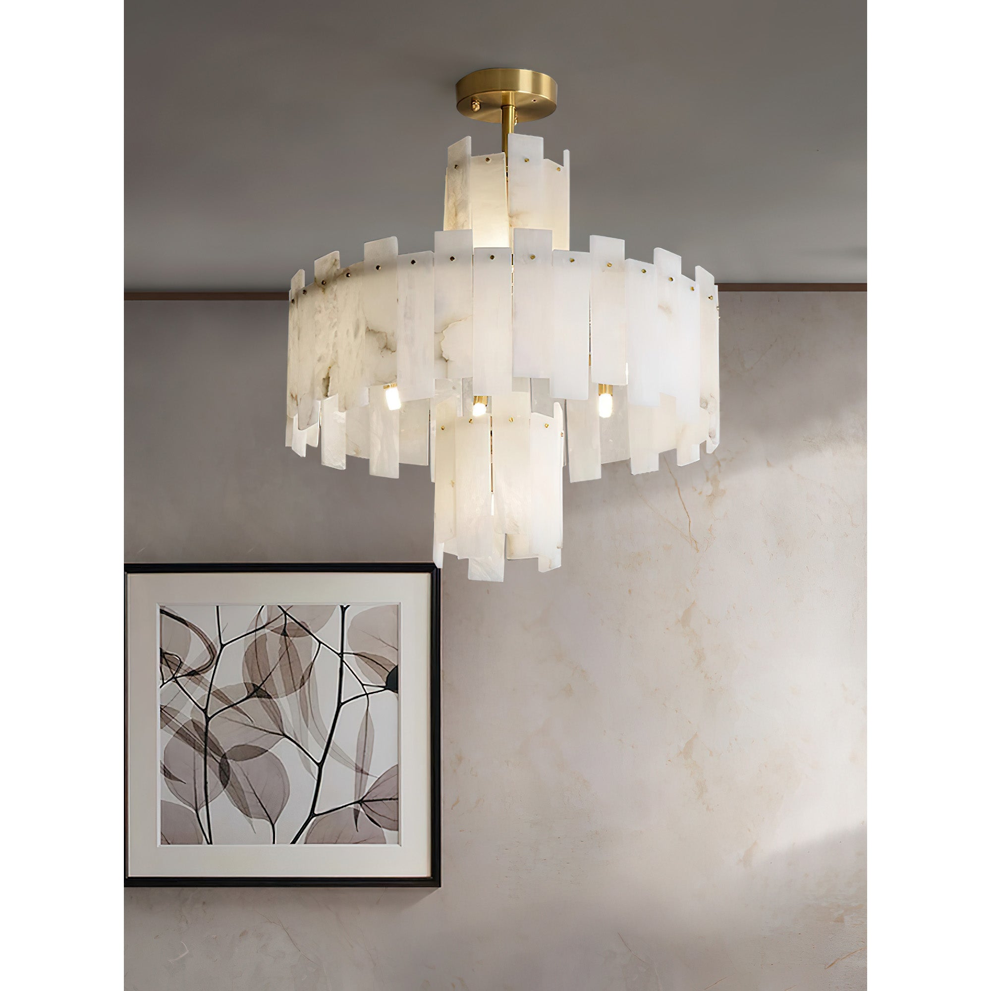 Clérachic Tiered Alabaster Chandelier lighting a plaster wall beside a framed botanical print in a warm-toned room.