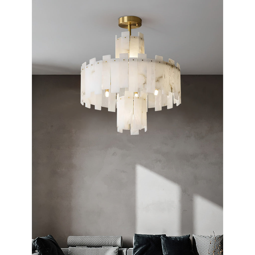 Clérachic Tiered Alabaster Chandelier over a grey seating area, daylight crossing the concrete wall behind it.