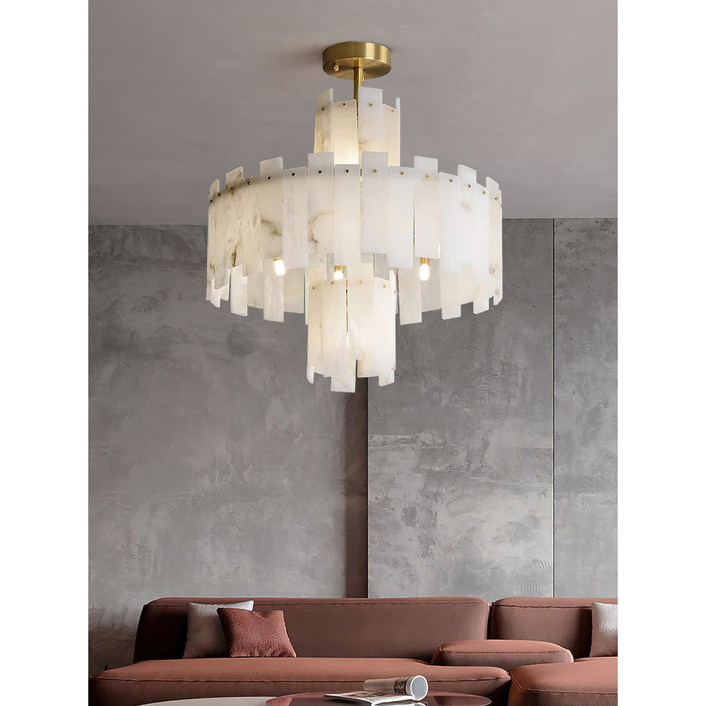 Clérachic Tiered Alabaster Chandelier glowing above a rust-coloured sofa against a grey concrete panel wall.