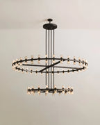 Clérachic two-tier chandelier in matte black, glass cylinders on a large and a small ring, hung from a round canopy on four rods.
