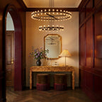 Clérachic matte black tiered chandelier in a panelled hallway above a burl console, gilt mirror and a pleated table lamp.