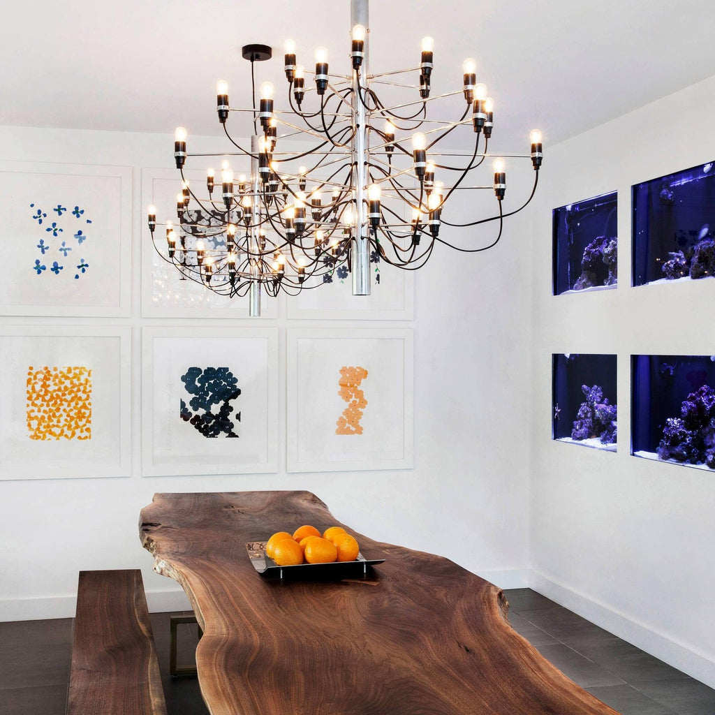 This Clérachic tiered chandelier hangs over a live-edge walnut dining table, with a bowl of oranges and framed prints on the wall.