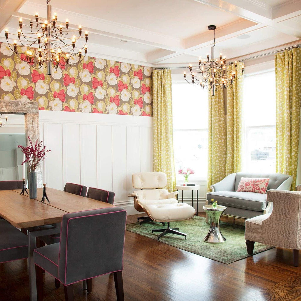 Two Clérachic tiered chandeliers hang in a coffered room with floral wallpaper, yellow curtains, a wooden table and a white lounge chair.