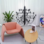 Close to a coral armchair and an oval side table, this matt black Clérachic chandelier shows its three tiers of slim arms and bulbs.