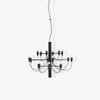 A small matt black Clérachic chandelier with curved cable arms, shown on a pale grey backdrop with a soft shadow.