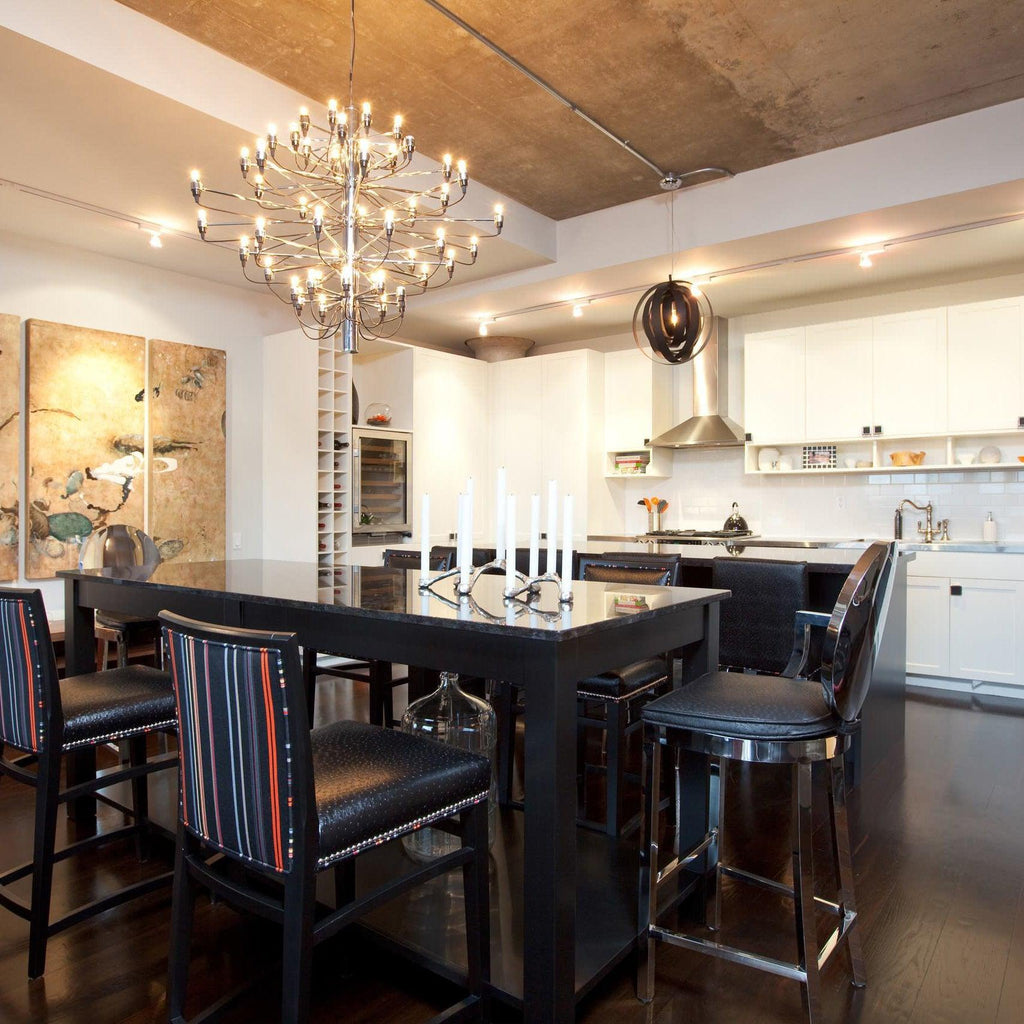 Over a dark dining table with leather stools, this Clérachic chandelier glows with exposed bulbs below an exposed concrete ceiling.