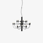 A compact Clérachic chandelier in matt black with slim looping arms and exposed bulbs, on a pale grey backdrop.