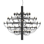 A large Clérachic chandelier in matt black, with many tiers of slim arms, looping cables and exposed bulbs, on white.