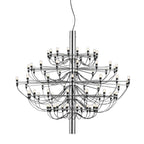 A large Clérachic chandelier with a polished chrome stem and many tiers of slim arms, on a plain white backdrop.