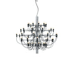 A Clérachic chandelier with a chrome stem, many tiers of slim arms and a ceiling hook above, on a white backdrop.
