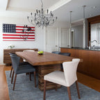 This Clérachic chandelier hangs in a kitchen-diner above a wooden table with leather chairs, a flag artwork beside the doors.