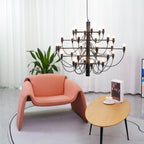 Seen close up, this matt black Clérachic chandelier hangs above a coral armchair and an oval table with a cup and book.