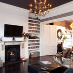 This Clérachic chandelier glows against a black ceiling above a fireplace and shelves of records.