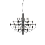 A compact Clérachic tiered chandelier in matt black, with three tiers of slim arms and exposed bulbs, on a white backdrop.
