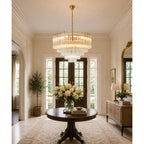 This Clérachic chandelier hangs in a bright entrance hall above a round wooden table holding a large bunch of white flowers.