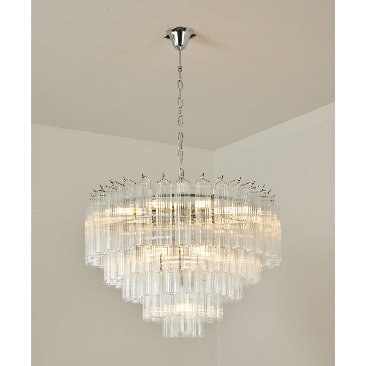 Lit Clérachic chandelier with chrome fittings, its stepped tiers of fluted glass rods shining in a room corner.