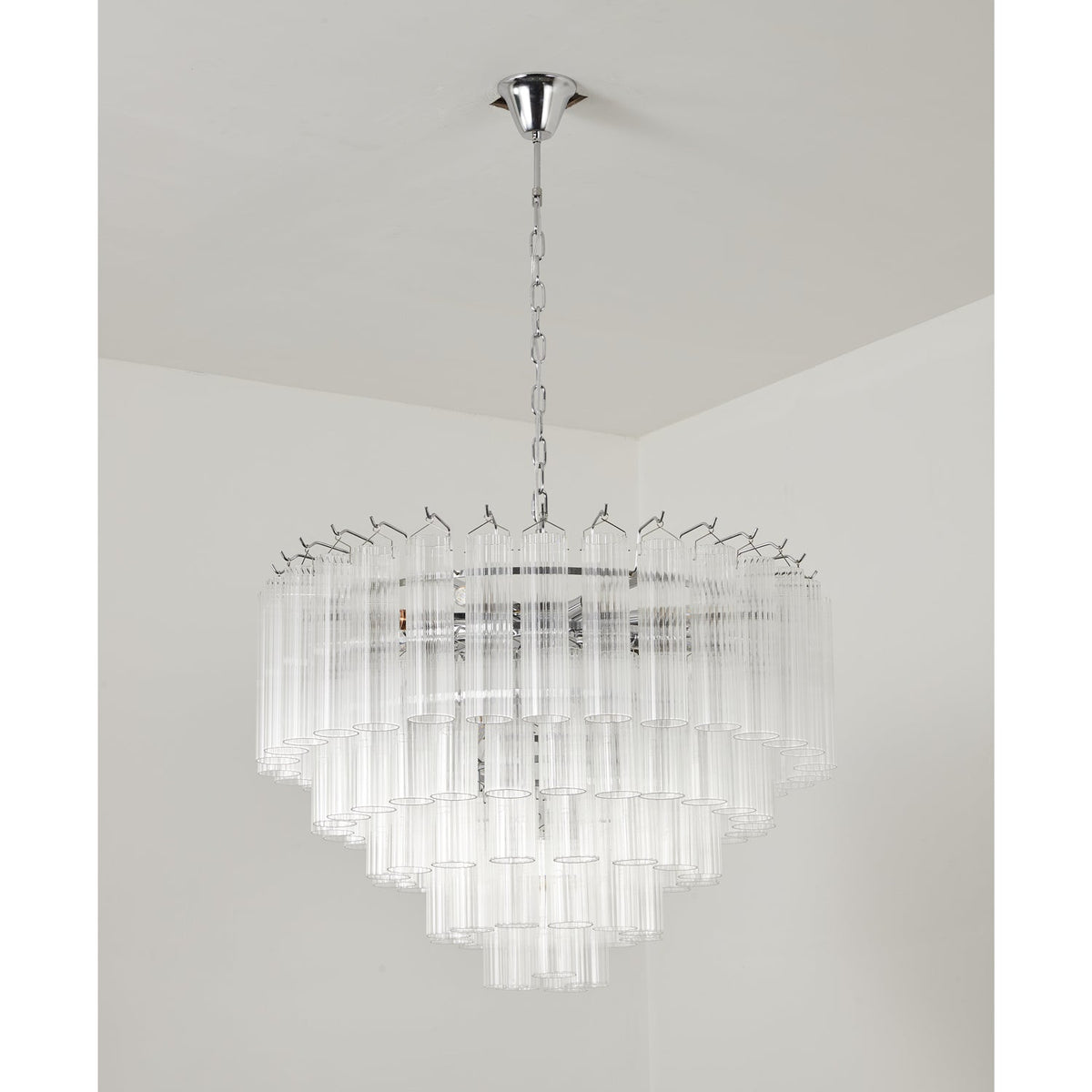 Clérachic chandelier in a chrome finish, unlit, its widest tier of glass rods spreading beneath a long chain.