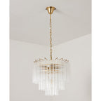 Unlit Clérachic chandelier with clear ribbed glass rods around a gold-toned frame, hanging from a short chain.