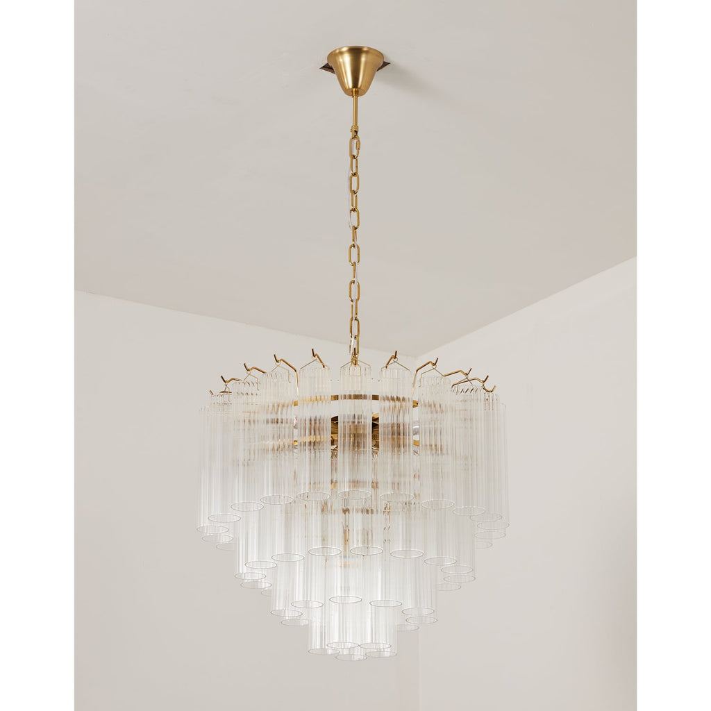 This Clérachic chandelier switched off, with several tiers of clear glass tubes and a gold-toned canopy above.