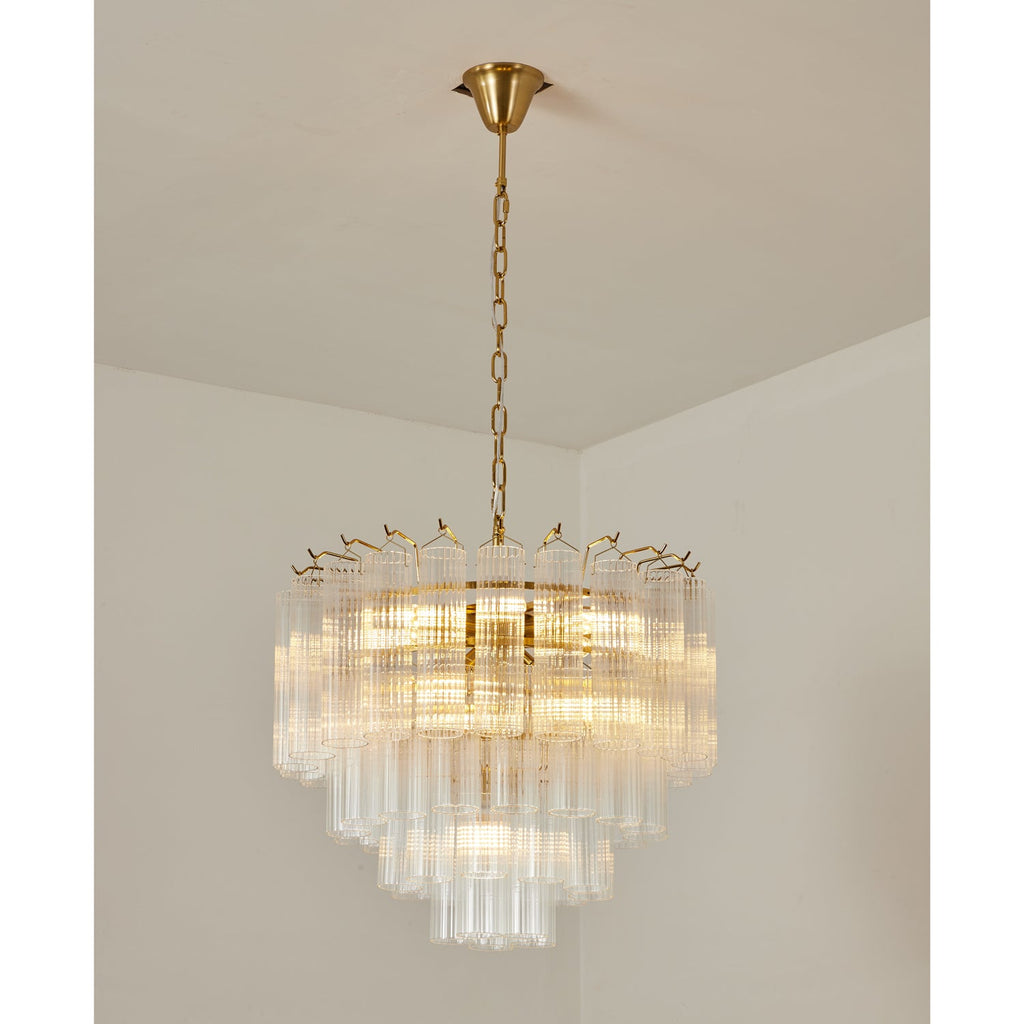 Clérachic tiered glass chandelier glowing evenly, its gold-toned chain rising to a small ceiling cup in a white corner.