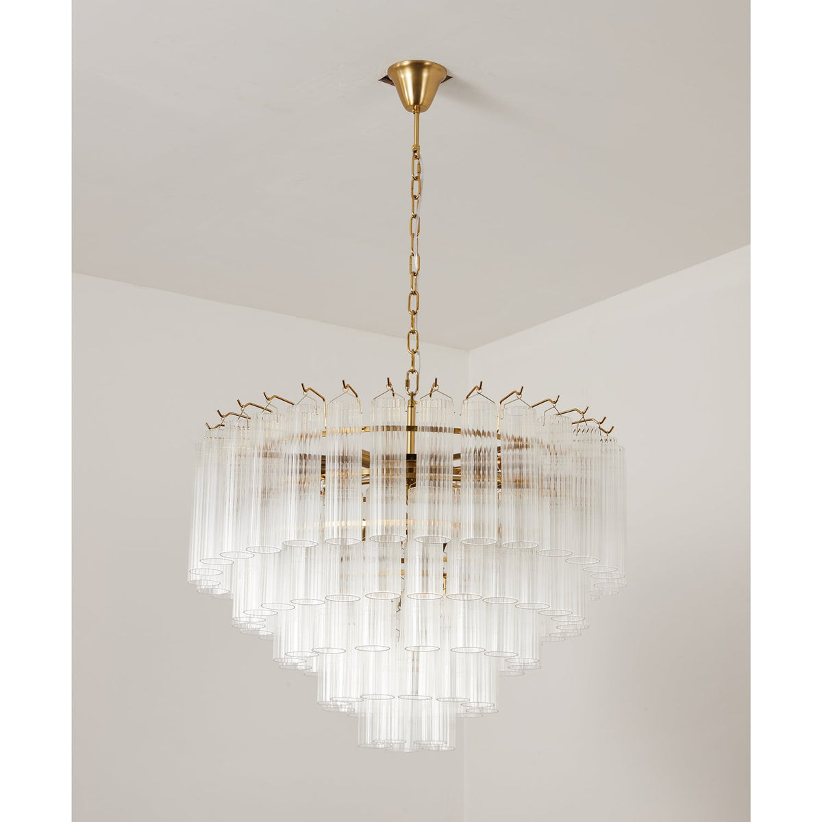 Large Clérachic chandelier, off, its tiers of clear glass tubes spreading wide beneath a gold-toned canopy.