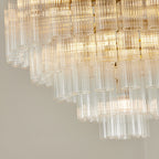 Close view of the lower tiers of this Clérachic chandelier, lit, with open-ended fluted glass rods in stepped rows.