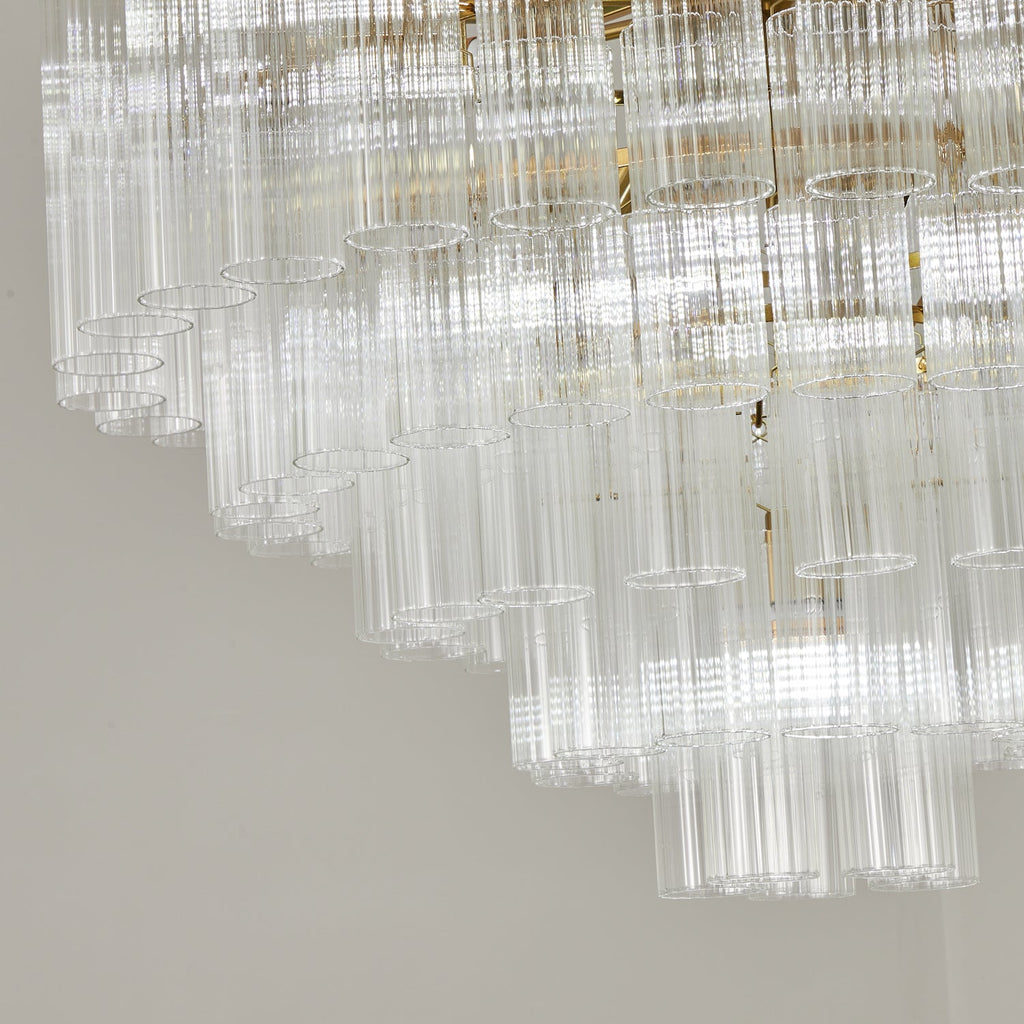 Close view of the stepped glass rods on this Clérachic chandelier, switched off, with the gold-toned frame behind them.