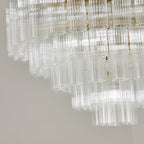 Close view of the stepped glass rods on this Clérachic chandelier, switched off, with the gold-toned frame behind them.
