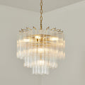 A Clérachic tiered glass chandelier shining against a pale wall, its gold-toned hooks visible around the upper rim.