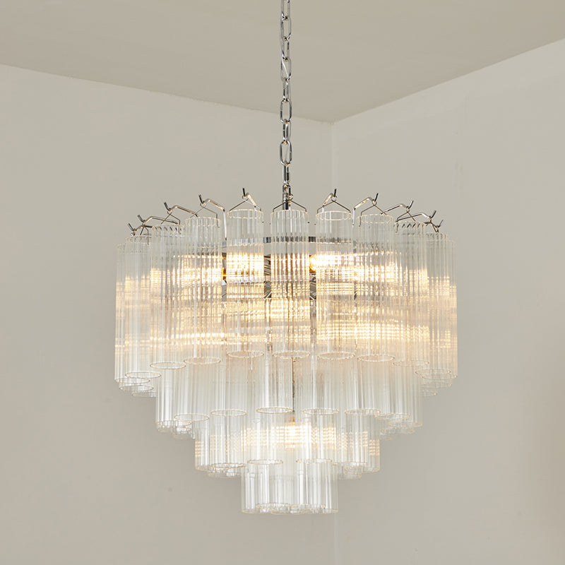 Chrome-fitted Clérachic glass chandelier glowing warm in a room corner, with the rods stepped in graduated lengths.