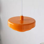 Underside angle of an orange Clérachic tiered pendant against a pale grey wall, showing the wide top disc and the small vent holes.