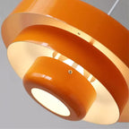 Close view of the glowing opening and stepped tiers of an orange Clérachic pendant, with a small screw on the lower ring.