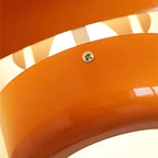 Close view of the glossy orange edge on a Clérachic pendant, with a small brass screw and the pale inner shade behind it.